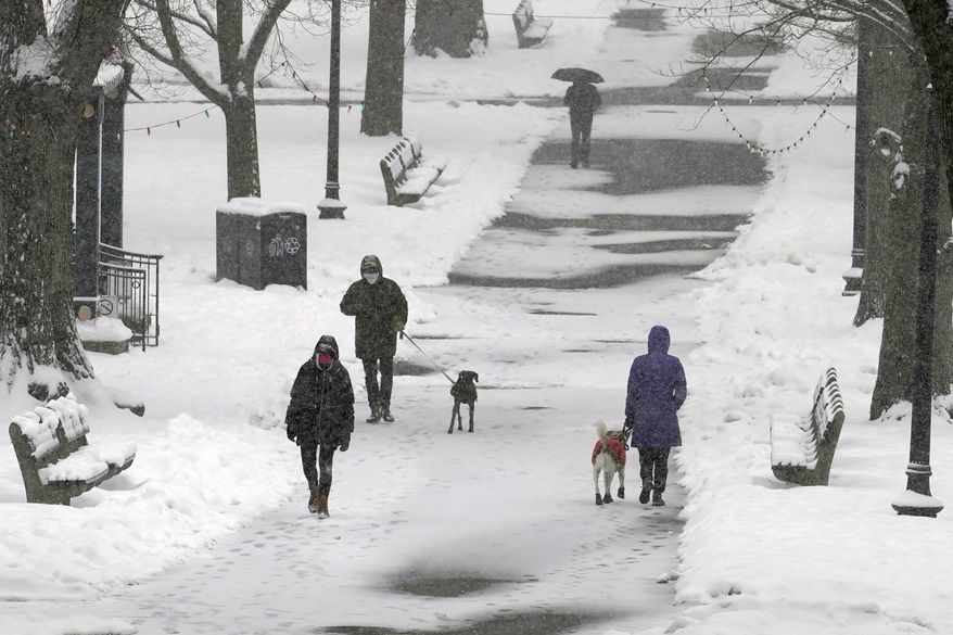 Pedestrians walk along a snow-covered path in the Boston Common, Tuesday, Feb. 9, 2021, in Boston. (AP Photo/Steven Senne)