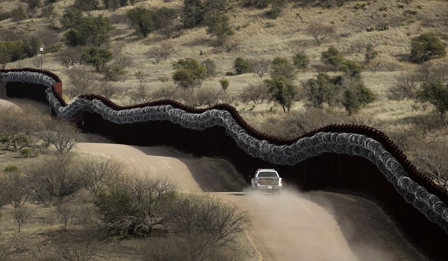 This March 2, 2019 photo shows a Customs and Border Control agent patrols on the US side of a razor-wire-covered border wall along the Mexico east of Nogales, Ariz. President Joe Biden rushed to send the most ambitious overhaul of the nation&#x27;s immigration system in a generation to Congress and signed nine executive actions to wipe out some of his predecessor&#x27;s toughest measures to fortify the U.S.-Mexico border. But a federal court in Texas suspended his 100-day moratorium on deportations. (AP Photo/Charlie Riedel,File)