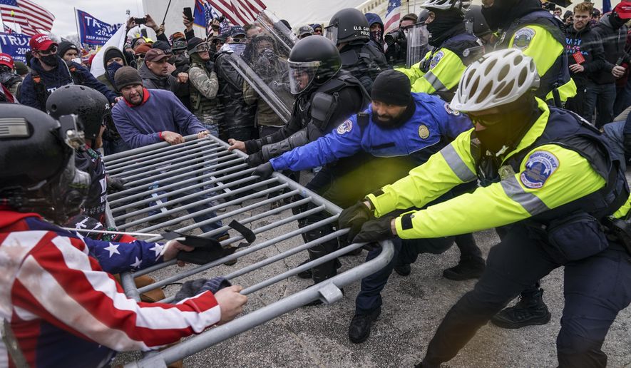 FILE - In this Jan. 6, 2021, file photo violent insurrectionists loyal to President Donald Trump supporters try to break through a police barrier at the Capitol in Washington. A month ago, the U.S. Capitol was besieged by Trump supporters angry about the former president's loss. While lawmakers inside voted to affirm President Joe Biden's win, they marched to the building and broke inside. (AP Photo/John Minchillo, File)