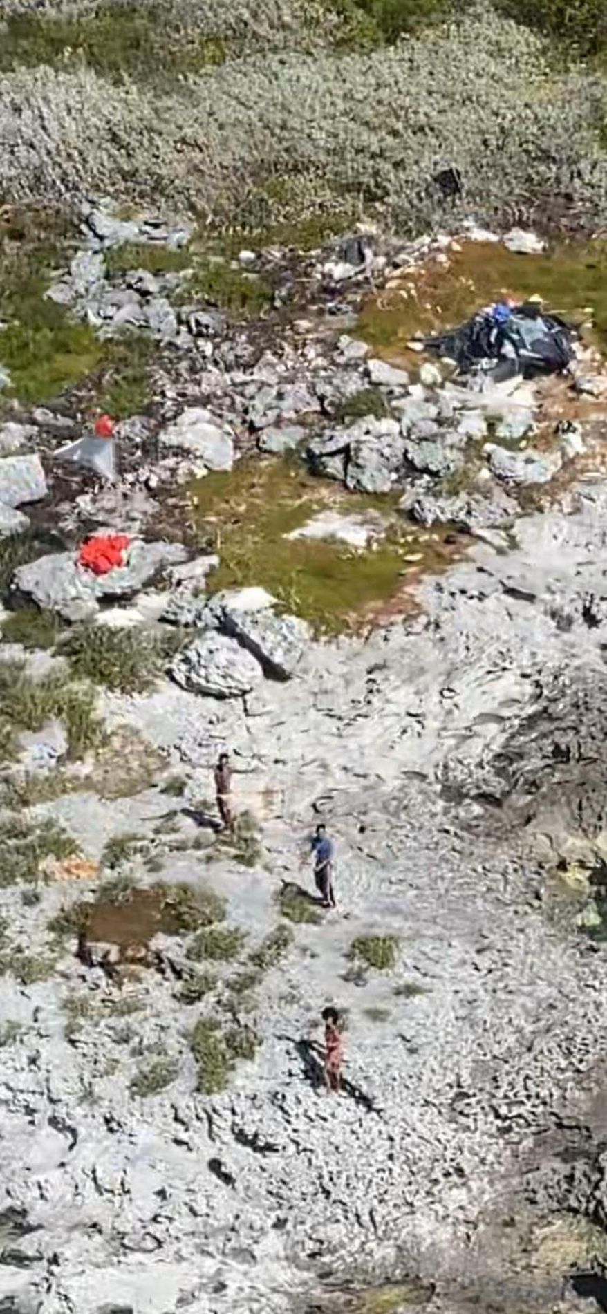 This photo provided by the U.S. Coast Guard shows three Cuban nationals being rescued from a deserted island between Florida and Cuba, Monday, Feb. 9, 2021. They waved flags to catch the attention of a Coast Guard helicopter crew that flew over the island while on a routine mission Monday. (U.S. Coast Guard via AP)