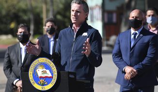 California Gov. Gavin Newsom, center, gestures in front of local officials while speaking about COVID-19 vaccines at the Fresno Fairgrounds, Wednesday, Feb. 10, 2021, in Fresno, Calif. (John Walker/The Fresno Bee via AP)