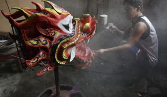 Robert Sicat sprays a protective coating on a Dragon head at a creekside slum at Manila&#x27;s Chinatown, Binondo Philippines on Feb. 4, 2021. The Dragon and Lion dancers won&#x27;t be performing this year after the Manila city government banned the dragon dance, street parties, stage shows or any other similar activities during celebrations for Chinese New Year due to COVID-19 restrictions leaving several businesses without income as the country grapples to start vaccination this month. (AP Photo/Aaron Favila)