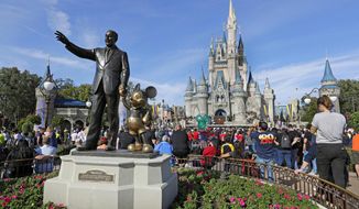 FILE - In this Jan. 9, 2019, file photo, guests watch a show near a statue of Walt Disney and Micky Mouse in front of the Cinderella Castle at the Magic Kingdom at Walt Disney World in Lake Buena Vista, Fla. The Walt Disney Co.&#39;s net income fell sharply in its most-recent quarter, as the coronavirus pandemic still weighs heavily on many of its businesses, from theme parks to movies, the company announced Thursday, Feb. 11, 2021. (AP Photo/John Raoux, File)