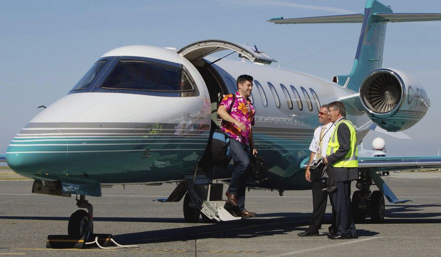 This Aug. 17, 2011 file photo, Jaeger Mah, left, is greeted by Vancouver International Airport CEO Larry Berg, right, and pilot Brent Fishlock as he steps off a Learjet upon arrival at the airport after a short tour in Richmond, B.C. No survivors were found after a small business jet with four people aboard crashed and burned near San Diego, knocking out power to hundreds of homes, authorities said. (Darryl Dyck/The Canadian Press via AP)