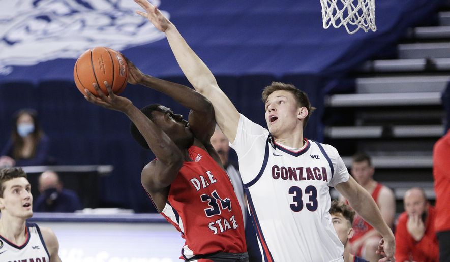 FILE - In this Dec. 29, 2020, file photo, Dixie State guard Emad Elniel (34) shoots and is fouled by Gonzaga forward Ben Gregg (33) during the second half of an NCAA college basketball game in Spokane, Wash. Gregg is among a small group of freshmen seizing an opportunity to play as midyear enrollees after the NCAA granted an extra year of eligibility to athletes in winter sports like basketball. (AP Photo/Young Kwak, File)