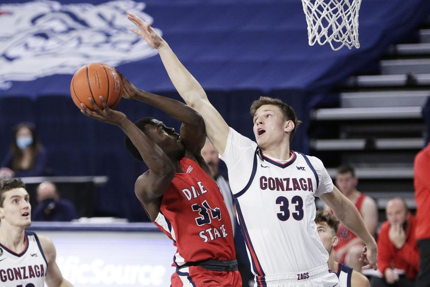 FILE - In this Dec. 29, 2020, file photo, Dixie State guard Emad Elniel (34) shoots and is fouled by Gonzaga forward Ben Gregg (33) during the second half of an NCAA college basketball game in Spokane, Wash. Gregg is among a small group of freshmen seizing an opportunity to play as midyear enrollees after the NCAA granted an extra year of eligibility to athletes in winter sports like basketball. (AP Photo/Young Kwak, File)