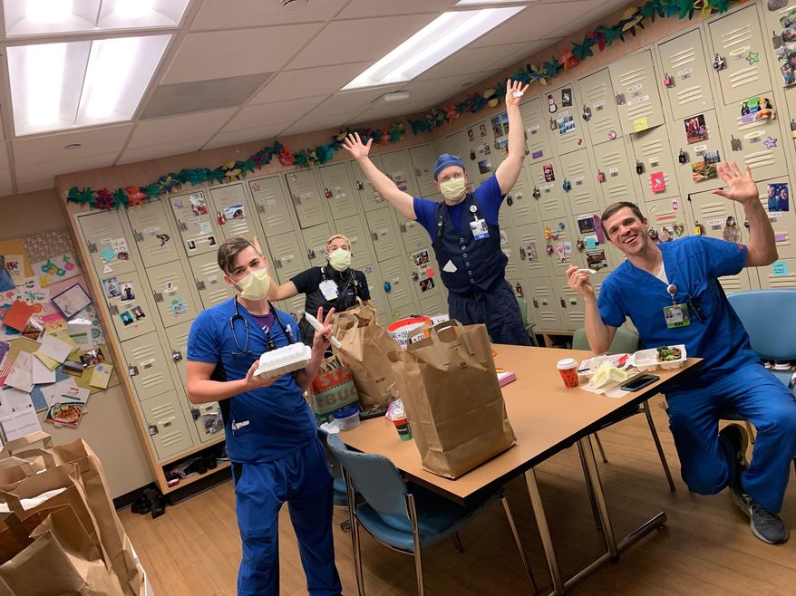 This photo provided by Brittney Caldera shows, from left to right, Oregon Health & Science University nurses Nick Greenwood, Callie Harling, Derrell Wheeler and Orion Meredith as they eat a meal delivered to the hospital's frontline COVID-19 health care workers in a break room, Jan. 10, 2021, at Oregon Health & Science University, in Portland, Ore. The program that provided the meals, funded by a grant from an Oregon-based insurance fund, recently expired but the hospital is hoping for new donations to reboot it as COVID-19 variants could cause a new surge of cases. (Brittney Caldera via AP)