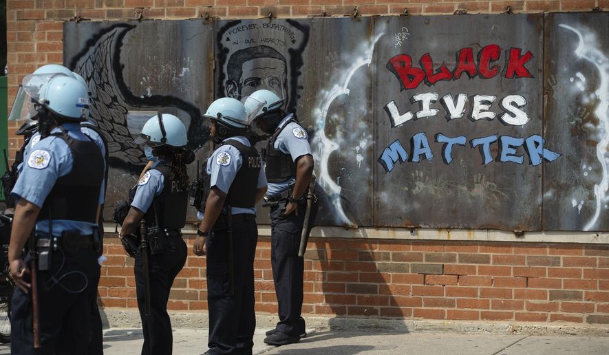 FILE - In this Aug. 15, 2020, file photo, police officers stand beside a mural for George Floyd in the Chicago neighborhood of Bronzeville during an anti-police brutality protest. In the last decade, high-profile police killings — including Floyd — have shaken the nation and led to widespread protests and calls for reform, including hiring more nonwhite and female officers. (Pat Nabong/Chicago Sun-Times via AP, File)