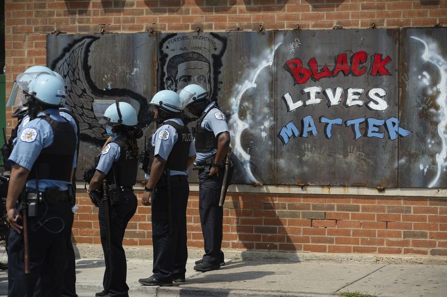 FILE - In this Aug. 15, 2020, file photo, police officers stand beside a mural for George Floyd in the Chicago neighborhood of Bronzeville during an anti-police brutality protest. In the last decade, high-profile police killings — including Floyd — have shaken the nation and led to widespread protests and calls for reform, including hiring more nonwhite and female officers. (Pat Nabong/Chicago Sun-Times via AP, File)