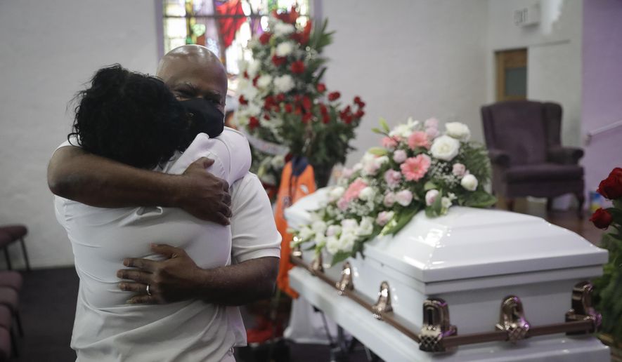 In this July 21, 2020, photo, Darryl Hutchinson, facing camera, is hugged by a relative during a funeral service for Lydia Nunez, who was Hutchinson's cousin at the Metropolitan Baptist Church in Los Angeles. Nunez died from COVID-19. California has edged past New York in the grim statistic of the number of deaths due to COVID-19, according Johns Hopkins University data reported Thursday, Feb. 11, 2021. (AP Photo/Marcio Jose Sanchez) **FILE**