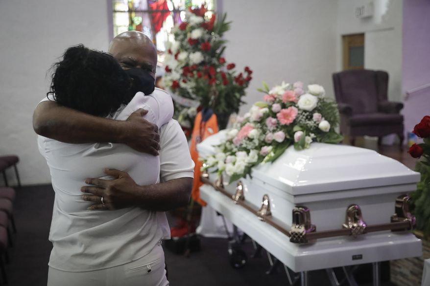 In this July 21, 2020, photo, Darryl Hutchinson, facing camera, is hugged by a relative during a funeral service for Lydia Nunez, who was Hutchinson's cousin at the Metropolitan Baptist Church in Los Angeles. Nunez died from COVID-19. California has edged past New York in the grim statistic of the number of deaths due to COVID-19, according Johns Hopkins University data reported Thursday, Feb. 11, 2021. (AP Photo/Marcio Jose Sanchez) **FILE**