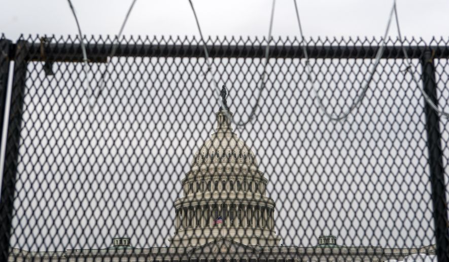 The U.S. Capitol is seen through a fence with barbed wire during the second impeachment trial of former President Donald Trump in Washington, Friday, Feb. 12, 2021. (AP Photo/Jose Luis Magana)