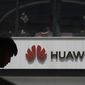 FILE - In this Thursday, May 16, 2019 file photo, a man is silhouetted near the Huawei logo in Beijing. Huawei took U.K. bank HSBC to court on Friday, Feb. 12, 2021 seeking documents the Chinese company says are key to its legal efforts to stop its chief financial officer from being extradited to the U.S. from Canada. (AP Photo/Ng Han Guan, file)