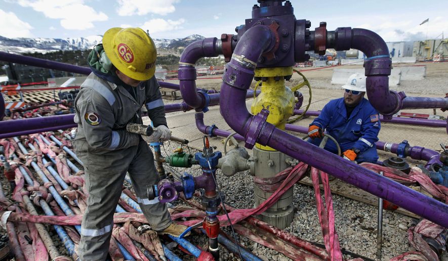 FILE - In this March 29, 2013, file photo, workers tend to a well head during a hydraulic fracturing operation outside Rifle, in western Colorado. The Interior Department said Friday, Feb. 12, 2021 that it is postponing onshore and offshore oil lease sales planned for next month in line with President Joe Biden's executive order on climate change. (AP Photo/Brennan Linsley, File)