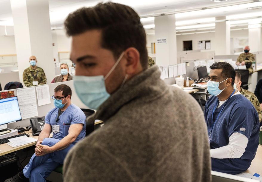 Dr. Paari Gopalakrishnan, right, chief medical officer of Care New England's Kent Hospital, holds a morning briefing with medical staff at a field hospital set up in a former bank call center to handle a surge of COVID-19 patients in Cranston, R.I, Monday, Dec. 28, 2020. "I'd love to take half of the patients from Kent but they're too sick," said Gopalakrishnan who runs the field hospital. (AP Photo/David Goldman)