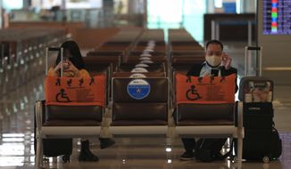 People wearing face masks wait for boarding at the Noi Bai airport in Hanoi, Vietnam, Friday, Feb.12, 2020. Fresh COVID-19 outbreak in Vietnam has slowed down business and travel during the popular lunar new year festival. (AP Photo/Hau Dinh)