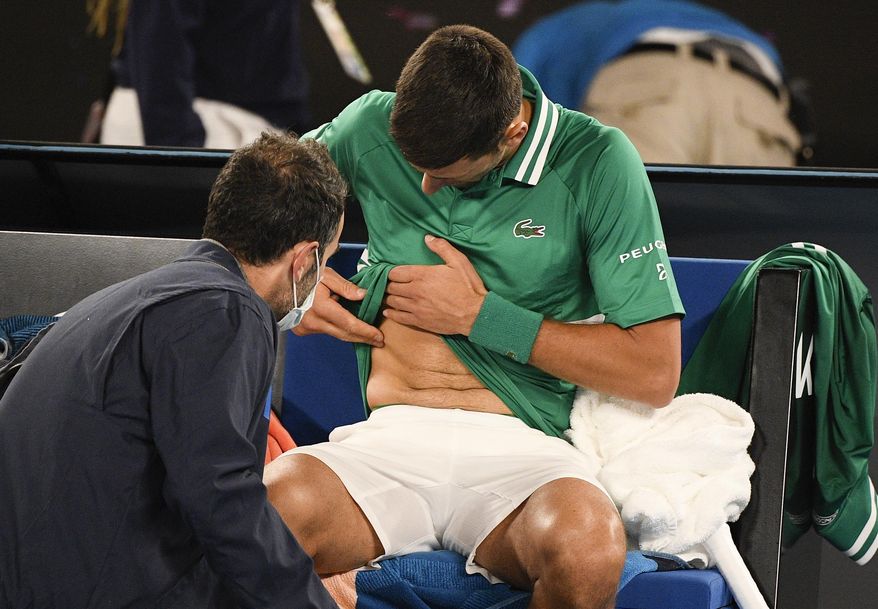 Serbia&#39;s Novak Djokovic receives treatment during his third round match against United States&#39; Talyor Fritz at the Australian Open tennis championship in Melbourne, Australia, Friday, Feb. 12, 2021.(AP Photo/Andy Brownbill)