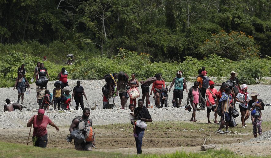 Migrants cross the Tuquesa river after a trip on foot through the jungle to Bajo Chiquito, Darien province, Panama, Wednesday, Feb. 10, 2021. Bajo Chiquito is the first population center that migrants coming from the Colombian border see when they cross over after several days of slogging through the jungle into Panama. (AP Photo/Arnulfo Franco)