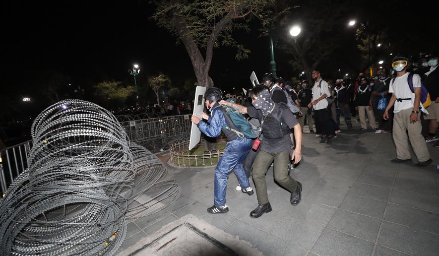 Pro-democracy protesters position themselves on the sidewalk during a rally in Bangkok, Thailand, Saturday, Feb. 13,2021. The rally in the Thai capital was organized by the Ratsadorn movement, which campaigned last year for Prime Minister Prayuth Chan-ocha and his government to step down, the constitution to be amended and the reform of the monarchy to make it more accountable.(AP Photo/Sakchai Lalit)