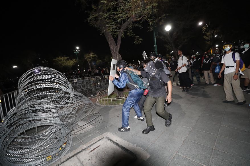 Pro-democracy protesters position themselves on the sidewalk during a rally in Bangkok, Thailand, Saturday, Feb. 13,2021. The rally in the Thai capital was organized by the Ratsadorn movement, which campaigned last year for Prime Minister Prayuth Chan-ocha and his government to step down, the constitution to be amended and the reform of the monarchy to make it more accountable.(AP Photo/Sakchai Lalit)