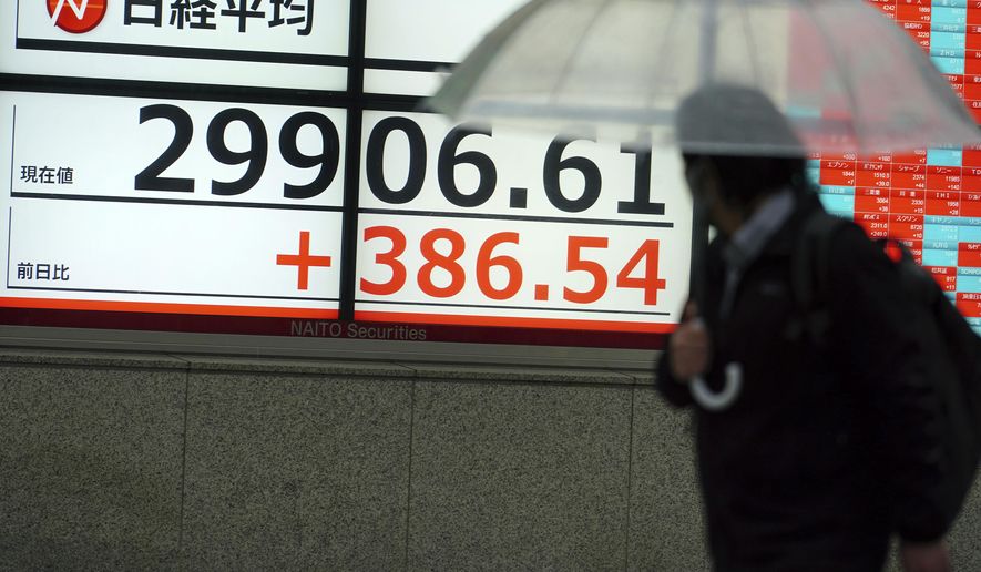 A man wearing a protective mask looks at an electronic stock board showing Japan's Nikkei 225 index at a securities firm Monday, Feb. 15, 2021, in Tokyo. Asian shares started the week off with a rally, as Japan’s Nikkei 225 index briefly topped 30,000 for the first time since August 1990. (AP Photo/Eugene Hoshiko)