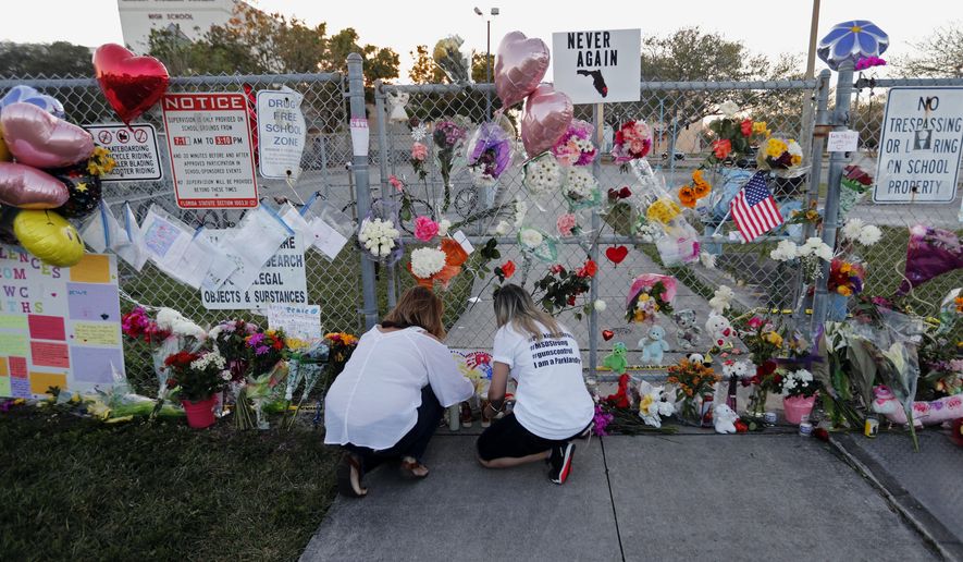 In this Feb. 18, 2018 file photo, people light candles at a makeshift memorial outside Marjory Stoneman Douglas High School, where 17 students and faculty were killed in a mass shooting days earlier in Parkland, Fla. (AP Photo/Gerald Herbert, File)