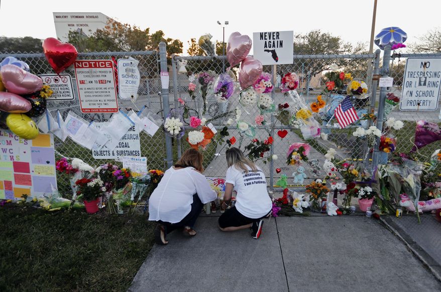 In this Feb. 18, 2018 file photo, people light candles at a makeshift memorial outside Marjory Stoneman Douglas High School, where 17 students and faculty were killed in a mass shooting days earlier in Parkland, Fla. (AP Photo/Gerald Herbert, File)