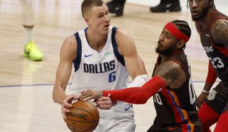 Portland Trail Blazers forward Carmelo Anthony (00) knocks the ball out of the hands of Dallas Mavericks center Kristaps Porzingis (6) during the first half of an NBA basketball game in Dallas, Sunday, Feb. 14, 2021. (AP Photo/Michael Ainsworth)