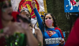 A woman dressed as a superhero and wearing a mask to curb the spread of the new coronavirus performs in the &amp;quot;Desliga da Justica&amp;quot; street band in Rio de Janeiro, Brazil, Sunday, Feb. 14, 2021. Their performance was broadcast live on social media for those who were unable to participate in the carnival due to COVID restrictions after the city&#x27;s government officially suspended Carnival and banned street parades or clandestine parties. (AP Photo/Bruna Prado)