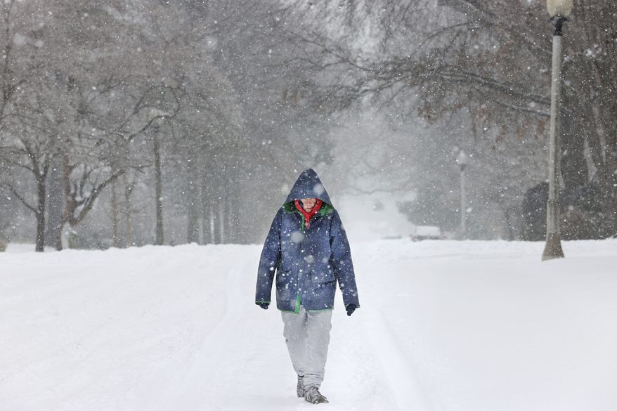 Margaret Bowden walks down the street under a heavy snowfall in Midtown Memphis, Tenn. as below freezing temperatures grip the mid-South on Monday, Feb. 15, 2021. (Joe Rondone/The Commercial Appeal via AP)