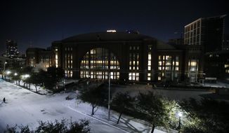 In order to save electricity, the promenade lights and screens are turned off in front of American Airlines Center which was to host the Nashville Predators and the Dallas Stars NHL hockey game, Monday, Feb. 15, 2021, in Dallas. Dallas Mayor Eric Johnson requested that the teams not play Monday due to a shortage of electricity in the region. (AP Photo/Brandon Wade)