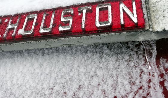 A sign is covered in ice and snow Monday, Feb. 15, 2021, in Houston. A winter storm dropping snow and ice sent temperatures plunging across the southern Plains, prompting a power emergency in Texas a day after conditions canceled flights and impacted traffic across large swaths of the U.S. (AP Photo/David J. Phillip)
