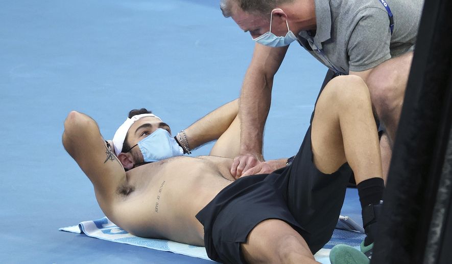 Italy's Matteo Berrettini, left, receives medical treatment during a break while playing Russia's Karen Khachanov during their third round match at the Australian Open tennis championships in Melbourne, Australia, Saturday, Feb. 13, 2021. (AP Photo/Hamish Blair)