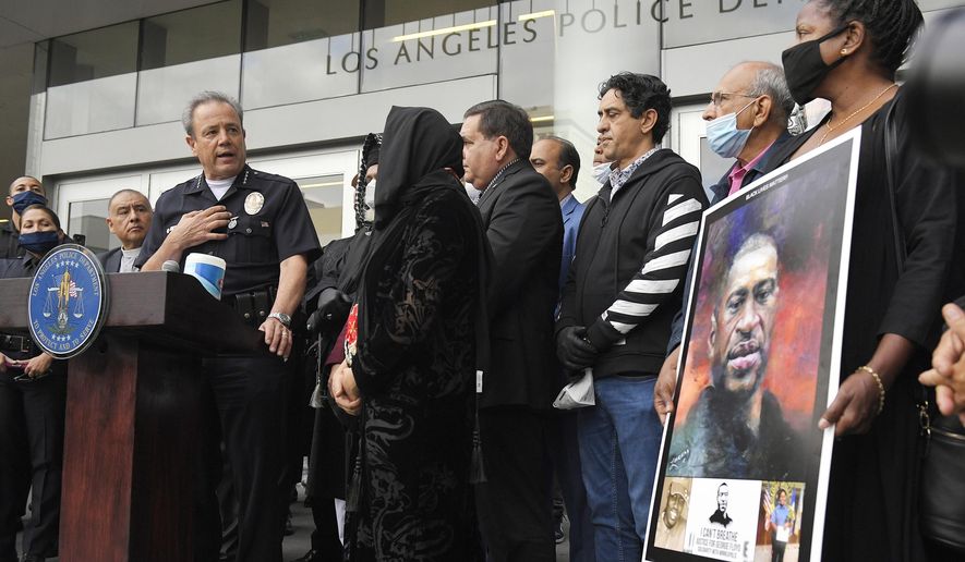 FILE - In this June 5, 2020, file photo, Los Angeles police chief Michel Moore, left, speaks as someone holds up a portrait of George Floyd during a vigil with members of professional associations and the interfaith community at Los Angeles Police Department headquarters in Los Angeles. The Los Angeles Police Department launched an internal investigation after an officer reported that a photo of Floyd with the words &amp;quot;You take my breath away&amp;quot; in a Valentine-like format was circulated among officers, according to a newspaper report. Moore said Saturday, Feb. 12, 2021, that investigators will try to determine how the image may have come into the workplace and who may have been involved, the Los Angeles Times reported. (AP Photo/Mark J. Terrill, File)
