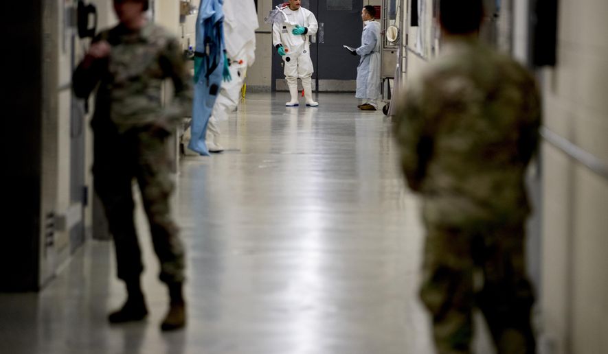 In this March 19, 2020, file photo, biological science specialists, background, wear biosafety protective clothing for handling viral diseases at U.S. Army Medical Research and Development Command at Fort Detrick in Frederick, Md. (AP Photo/Andrew Harnik) ** FILE **
