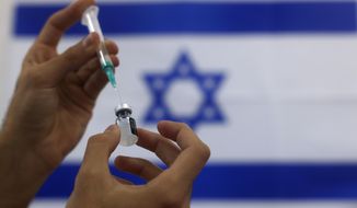 In this Thursday, Jan. 7, 2021, file photo, an Israeli military paramedic prepares a Pfizer COVID-19 vaccine, to be administered to elderly people at a medical center in Ashdod, southern Israel. After racing to a quick start, Israel is blaming online misinformation for a sudden slowdown in its campaign to vaccinate its adult population. (AP Photo/Tsafrir Abayov, File)