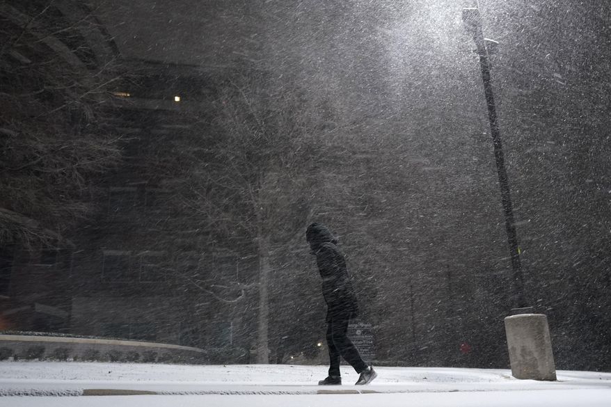 A woman walks through falling snow in San Antonio, Sunday, Feb. 14, 2021. Snow and ice blanketed large swaths of the U.S. on Sunday, prompting canceled flights, making driving perilous and reaching into areas as far south as Texas’ Gulf Coast, where snow and sleet were expected overnight. (AP Photo/Eric Gay)