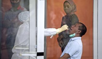 A man reacts as a medical worker collects his nasal swab samples during a test for coronavirus at North Sumatra University Hospital in Medan, North Sumatra, Indonesia, Tuesday, Feb. 16, 2021. Indonesia has recorded more coronavirus cases than any other country in Southeast Asia. (AP Photo/Binsar Bakkara)