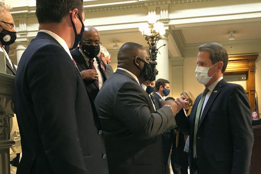 Georgia Gov. Brian Kemp, right, bumps fists with Democratic state Rep. Carl Gilliard of Garden City on Tuesday, Feb. 16, 2021, at the state Capitol in Atlanta. The Republican Kemp announced a plan to abolish Georgia's citizen's arrest law, partly blamed in the 2020 shooting death of Ahmaud Arbery near Brunswick, Ga. (AP Photo/Jeff Amy)