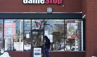 FILE - In this Jan. 28, 2021 file photo, a customer checks on his cellphone as he walks to a GameStop store in Vernon Hills, Ill. The frenzy around GameStop’s stock may have quieted down, but the outsized influence small investors had in the saga is likely to stick around. While no one expects another supernova like GameStop, the tools that smaller investors employed to supercharge its stock can be used again and again.  (AP Photo/Nam Y. Huh, File)