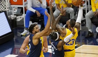 Los Angeles Lakers&#x27; LeBron James (23) shoots as Minnesota Timberwolves&#x27; Karl-Anthony Towns, left, and Jarred Vanderbilt (8) defend in the first half of an NBA basketball game, Tuesday, Feb. 16, 2021, in Minneapolis. (AP Photo/Jim Mone)
