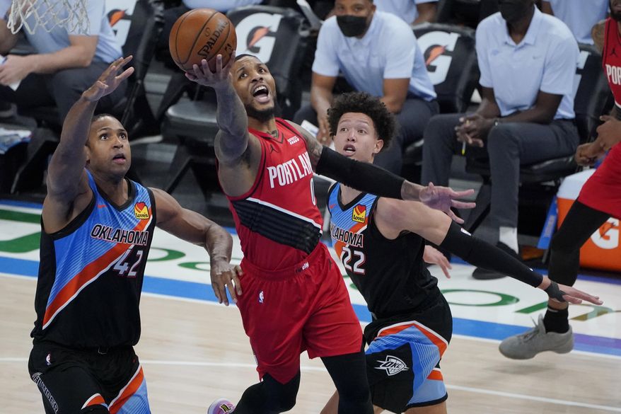 Portland Trail Blazers guard Damian Lillard (0) shoots between Oklahoma City Thunder center Al Horford (42) and center Isaiah Roby (22) in the second half of an NBA basketball game Tuesday, Feb. 16, 2021, in Oklahoma City. (AP Photo/Sue Ogrocki)