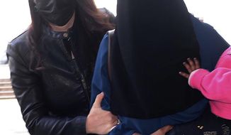 A woman, who was identified only by her initials S.A., one of three New Zealand nationals, is escorted by a Turkish police officer, left, to the local courthouse in Hatay, Turkey, Monday, Feb. 15, 2021.  According to a statement Monday by Turkey&#39;s Defense Ministry the 26-year old woman identified as S.A. is wanted on an Interpol notice for allegedly belonging to the extremist Islamic State group. (DHA via AP)