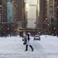 A woman crosses Wabash Avenue Tuesday, Feb. 16, 2021, after an overnight storm dumped up to 18.5 inches in the Chicago area. (AP Photo/Charles Rex Arbogast)