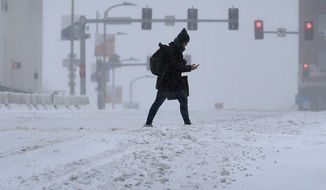 A pedestrian crosses Market Street during a snowstorm in downtown St. Louis on Monday, Feb. 15, 2021. The brutally cold weather is expected to continue through Saturday with more snow in the forecast for Wednesday and Thursday. (David Carson/St. Louis Post-Dispatch via AP)