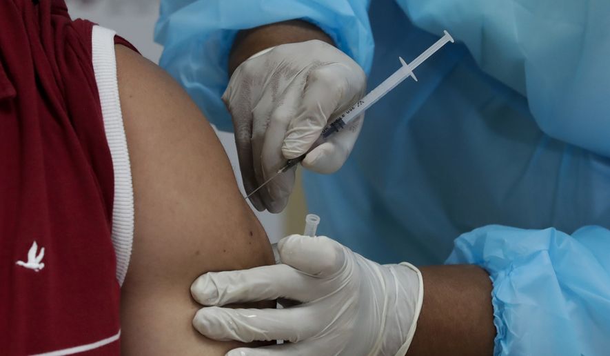 In this file photo, a health worker gets a second shot of the Pfizer-BioNTech vaccine for COVID-19 at Santo Tomas Hospital in Panama City, Wednesday, Feb. 17, 2021, on the day the second vaccine shipment arrived. (AP Photo/Arnulfo Franco) **FILE**