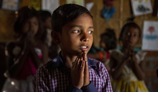 Imradul Ali, 10, prays with others in a classroom in a school near a landfill on the outskirts of Gauhati, India, Friday, Feb. 5, 2021. Once school is done for the day, Ali, rushes home to change out of his uniform so that he can start his job as a scavenger in India’s remote northeast. Coming from a family of scavengers or “rag pickers," Ali started doing it over a year ago to help his family make more money. Ali says he doesn’t want to spend his life doing this, but he doesn’t know what the future holds. (AP Photo/Anupam Nath)