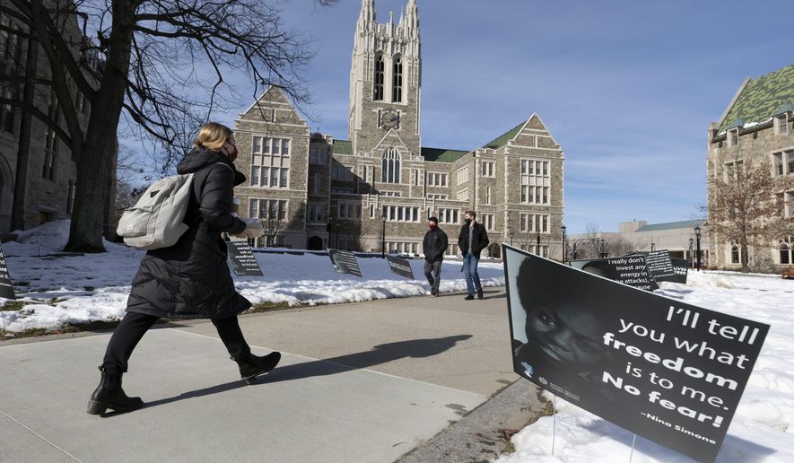 Students walk past Black History Month posters on the Boston College campus, Wednesday, Feb. 17, 2021, in Boston. Harassment by white male students targeting Black and Latina women housed in a Boston College dormitory has revived concerns about racism on campus. (AP Photo/Michael Dwyer)