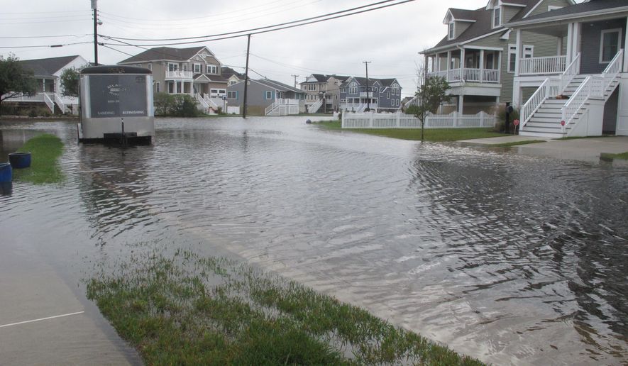 Flood waters cover the street, sidewalks and lawns of a neighborhood in Ocean City, N.J. on Oct. 30, 2020. The city is dealing with the costs of rising sea levels, both in monetary terms and in the disruption that recurring flooding brings. (AP Photo/Wayne Parry)