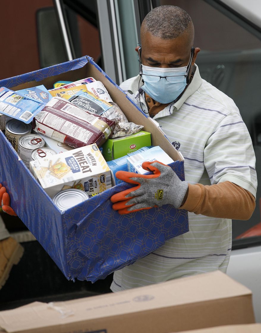 Maurice Davis, order selector, helps unload food donations from a Masonicare van at Connecticut Food Bank in Wallingford, Conn., Tuesday, Jan. 19, 2021. Masonicare delivered 5,488 pounds of food, plus a monetary donation of $1,364, to Connecticut Food Bank headquarters Tuesday that had been collected in a month-long drive. (Dave Zajac/Record-Journal via AP)